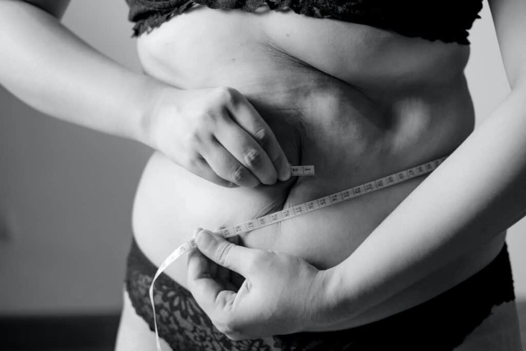 grayscale photo of woman holding her breast. Will progesterone help me lose weight?