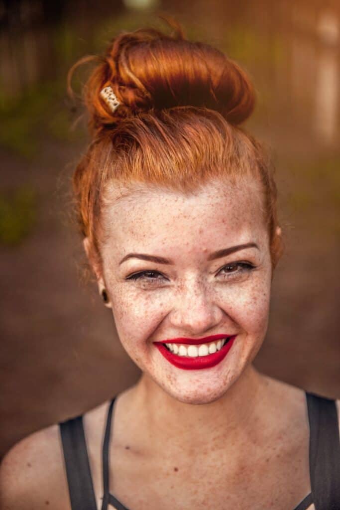 woman taking photo while showing smile. Can you still get freckles with sunscreen on?