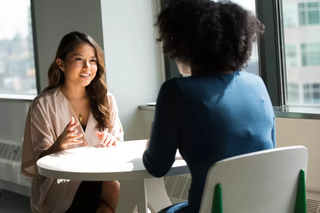 two women sitting on chair. how to manifest a job