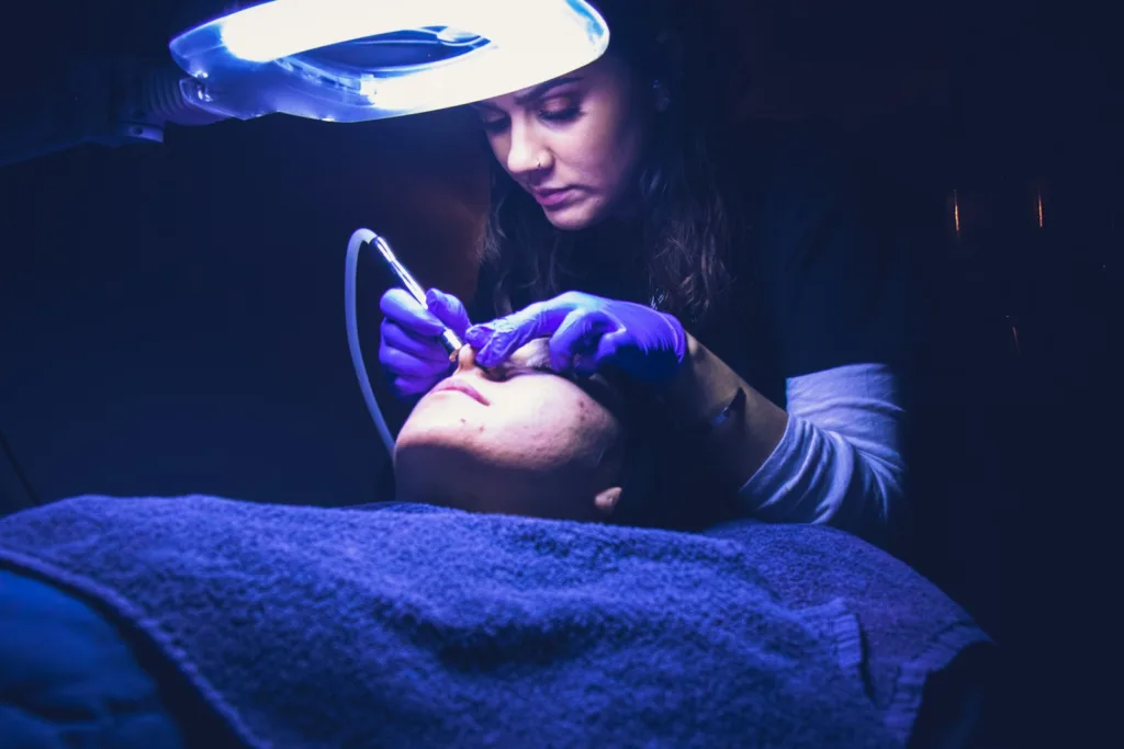 woman fixing another person's face, pros and cons of microdermabrasion