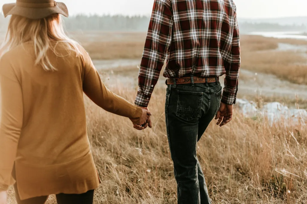 man and woman walking along grass field while holding hands. Dating at 50 after divorce